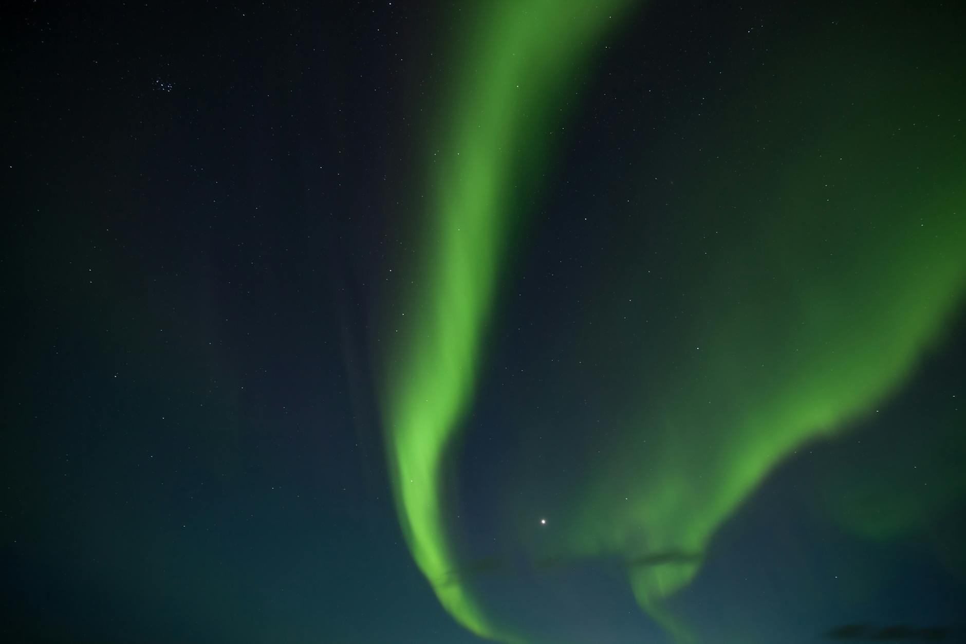 Vibrant green and purple northern lights dancing over a snow-covered Icelandic landscape at night.